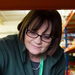 A female foodbank volunteer stacking shelves