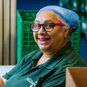 Volunteer looking into camera smiling in a food bank store room