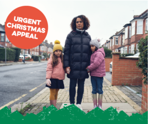 A woman with her two children, dressed in winter clothing, standing on a residential street. Text reads "Urgent Christmas appeal"