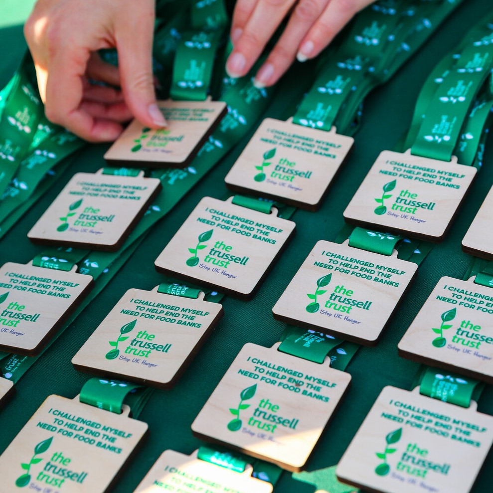A pair of hands arranges Trussell Trust medals laid out on a table.
