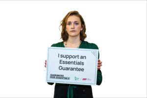 Actor Charlotte Ritchie holds up a sign that reads 'I support an Essential Guarantee'.