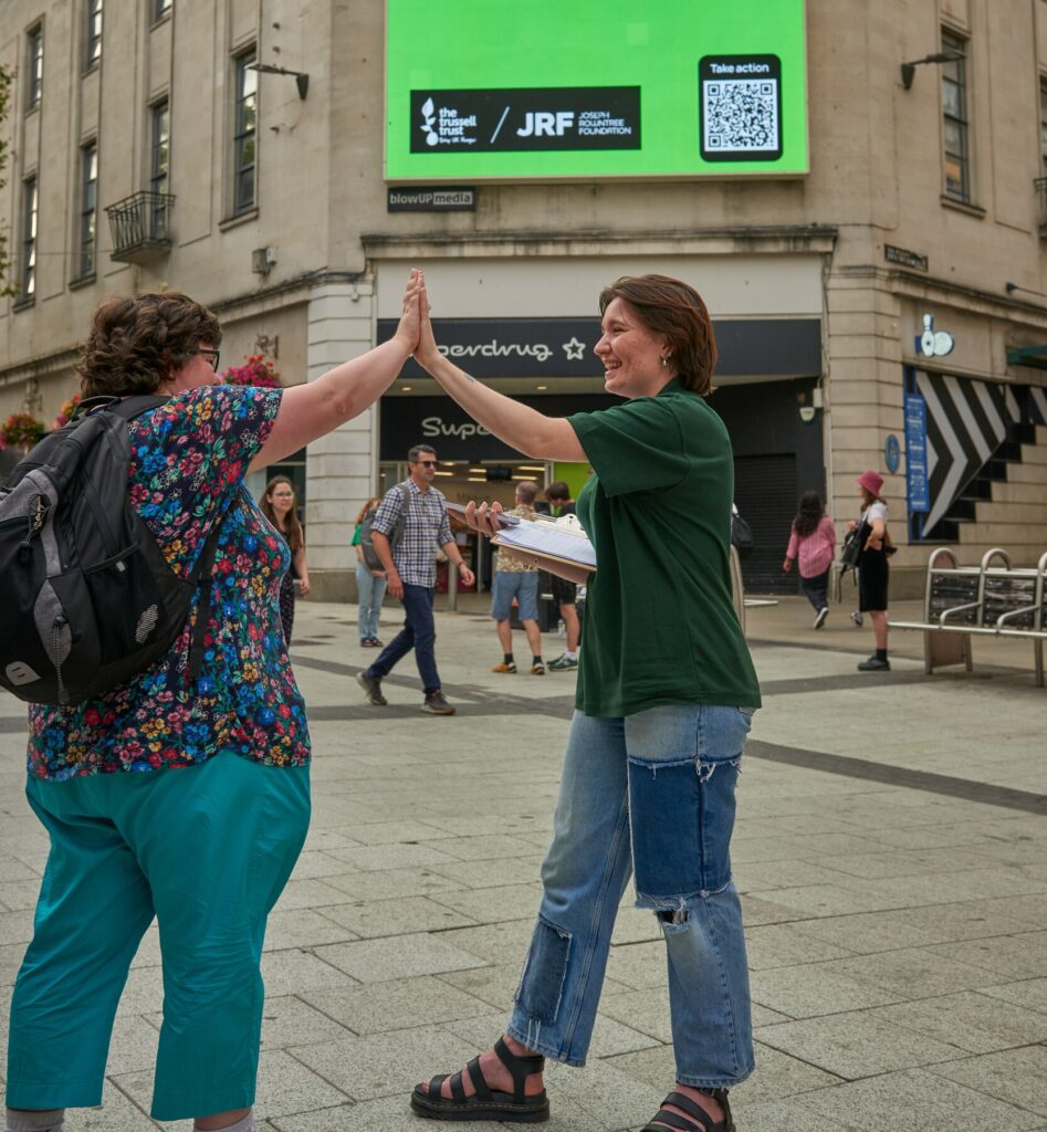 Two women high five outside a shop at the Trussell Trust Day of Action in Cardiff
